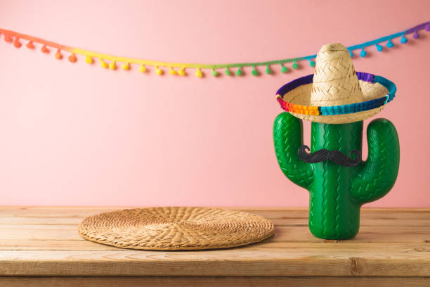 istock Empty wooden table with wicker place mat  and cactus decoration over pink wall  background. Mexican party mock up for design and product display 1482411957