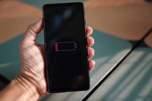 istock Man holding his smartphone showing low battery level on screen 1482413879