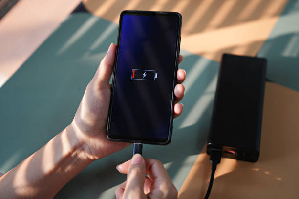 Woman hand plugging the charger into smart phone at the coffee shop, natural morning sunlight Woman hand plugging the charger into smart phone at the coffee shop / cafe, natural morning sunlight portable power bank stock pictures, royalty-free photos & images