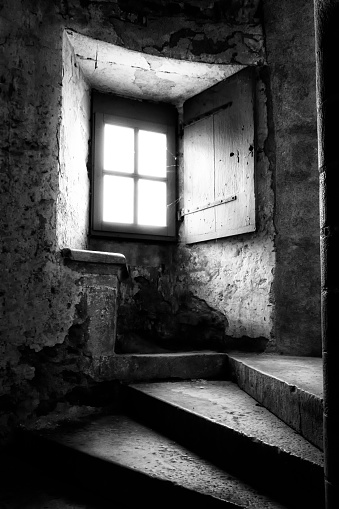 In the medieval village of Caylus, a stone spiral staircase and an old window with an interior shutter