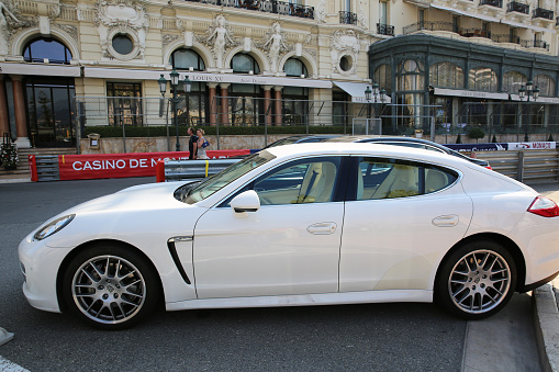 Monte-Carlo, Monaco - May 17, 2016: White Porsche Panamera 4S parked in front of the famous Hotel de Paris and Louis XV Restaurant in Monte Carlo, Monaco, with Formula 1 Grand Prix safety barriers
