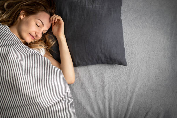 istock Pretty, young woman sleeping in her bed late in the morning on a weekend 1482420708