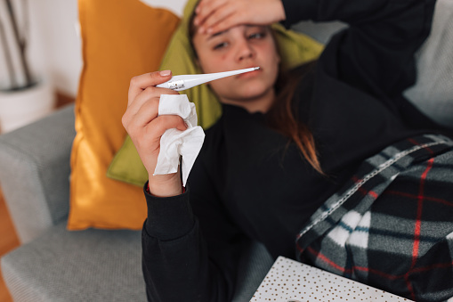 Mature father blowing nose of small sick son indoors at home.