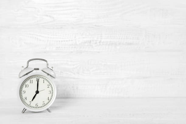 istock Front view white desk with alarm clock copy space. Morning background banner with free space for text. Minimalistic concept, workspace, time to work. Blank workplace. Office mock-up. 1482423432