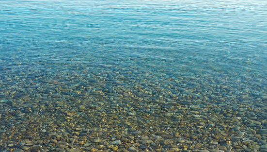 Photo beautiful seascape. A calm transporent water surface with pebbles stone under water surface.