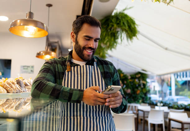 istock Waiter working at a cafe and using his cell phone during his break 1482426137