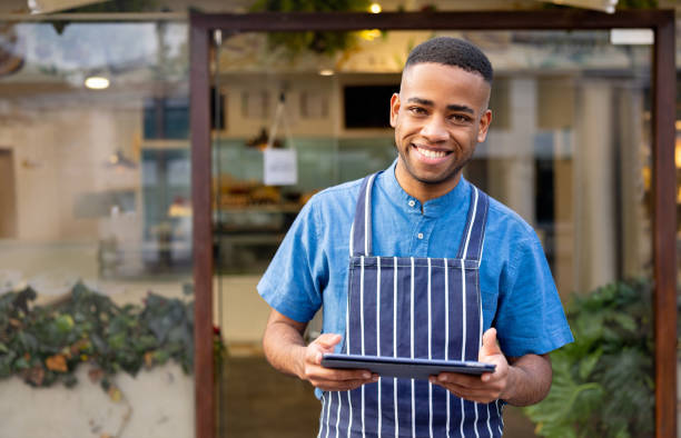 istock Happy waiter working at a cafe using a tablet computer and looking at the camera 1482426161
