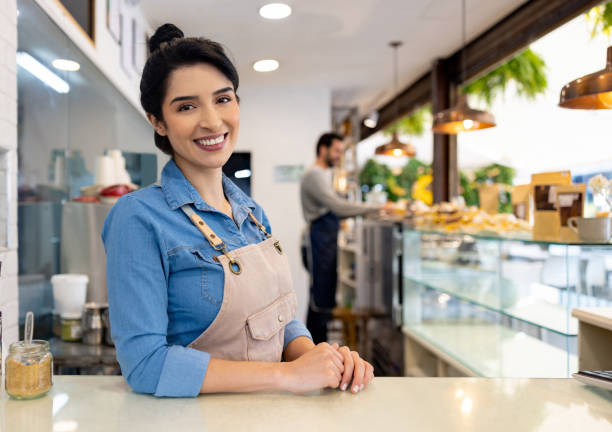 istock Happy waitress smiling behind the counter while working at a cafe 1482426175