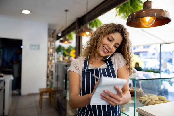 istock Happy waitress taking a delivery order on the phone at a cafe 1482426225