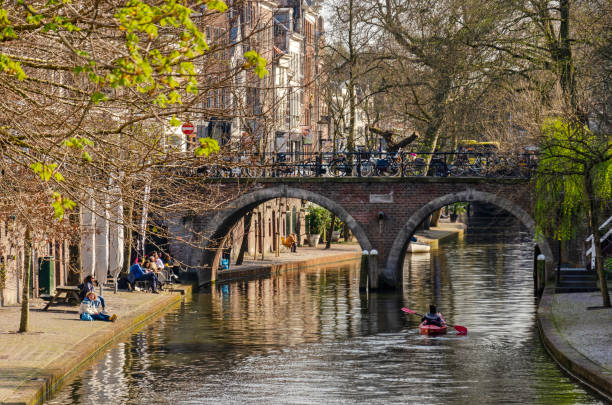 Utrecht, The Netherlands, April 9, 2023: people enjoying the springtime sun and others canooing on the water of the Oude Gracht (Old Canal)