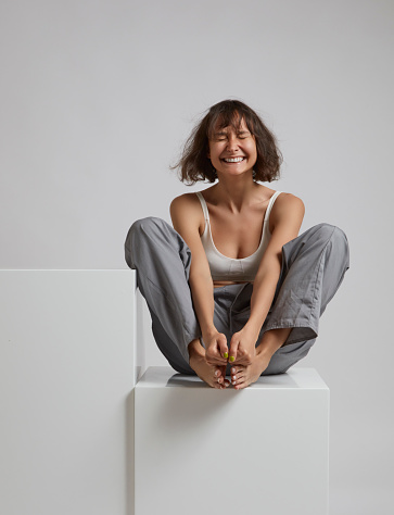 Young woman sitting on white box.