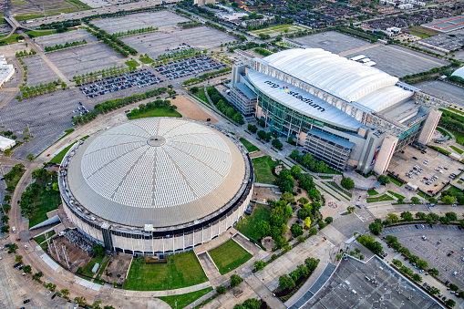 Houston, United States - April 13, 2023:  Aerial view of both the NRG Stadium, home to the NFL's Houston Texans, and the historic Astrodome, the first indoor sports arena, now listed as a historic site shot from an altitude of about 600 feet overhead during a helicopter photo flight.