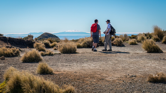Two people looking at Mt Ruapehu and Mt Ngauruhoe in the distance, view from Pouakai circuit track. Egmont National Park, New Zealand.