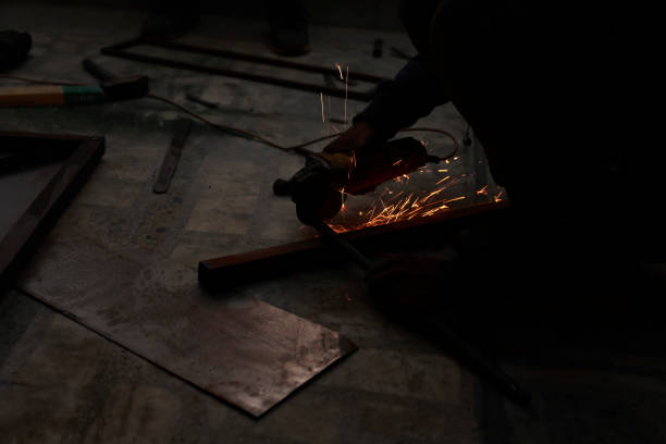 istock Close-up view strong man master without gloves on arms, performs metal cutting with an angle grinder in the garage workshop, blue and orange sparks fly to the sides 1482441998