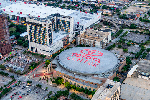 Houston, United States - April 13, 2023:  Aerial view of the Toyota Center, the home of the NBA's Houston Rockets; the sign illuminated at dusk, shot from about 600 feet in altitude from an orbiting helicopter.