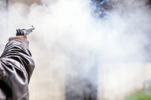 Unrecognizable man shoots with a black powder revolver