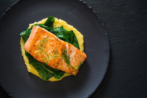 Roasted salmon fillet on cornmeal bed and spinach.