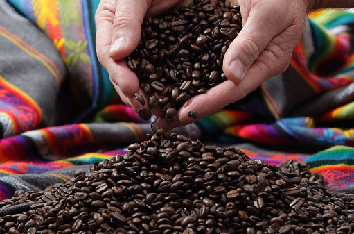 Coffee Beans in a mound with a man holding coffee beans, bright colorful background.