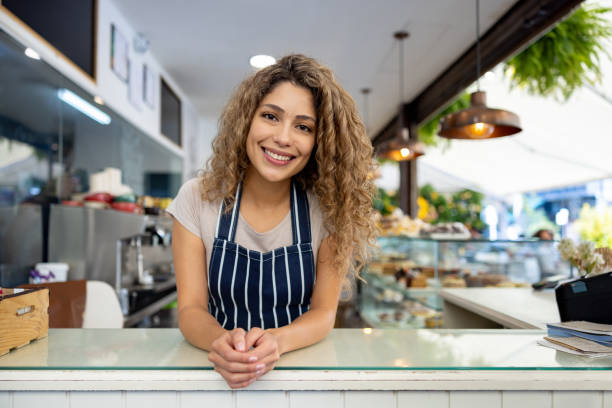 istock Happy waitress smiling behind the counter while working at a cafe 1482449537