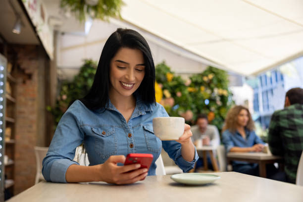 istock Happy woman at a cafe drinking coffee while looking at social media 1482449624