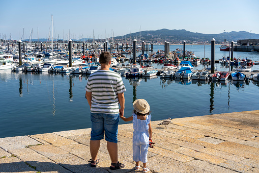 father and daughter looking at the boats from the harbour