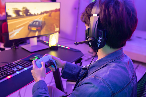 Male Gamer Playing  Driving Game with Game Controller in Neon Game Room