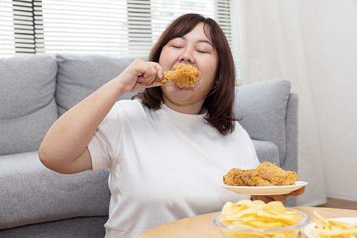 Overweight Asian Woman Enjoy Eatting Fried Drumstick Chicken