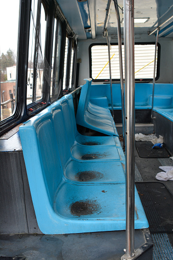 Dirty and broken passenger seats sit empty on an abandoned electric bus.