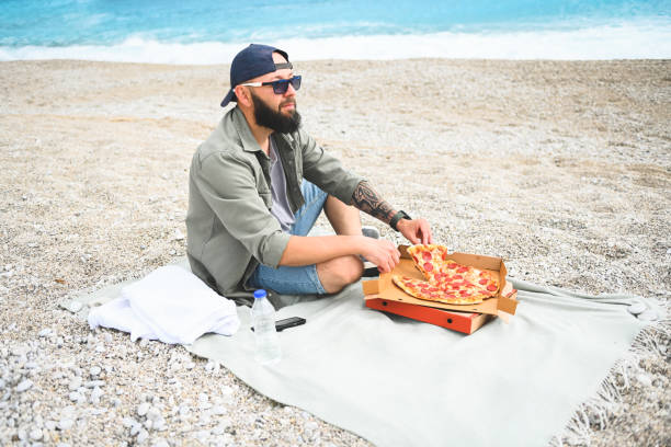 istock man resting on the beach and eat pizza 1482465289