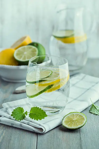 Photo of Glass of water with lemon and lime on kitchen table