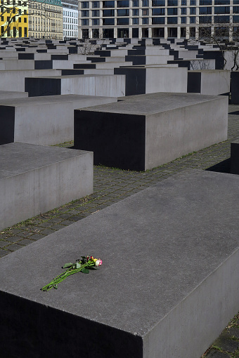 a single rose place on a granite block in the Field of Stelae, a plaza in downtown Berlin, Germany, a memorial to the the Jews killed in Europe