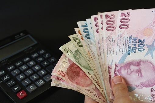 Una persona sostiene una pila de billetes turcos frente a una calculadora. photo