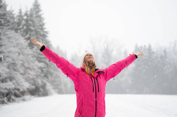 Happy young woman with a smile on her face standing outside in snowy winter nature enjoying life stock photo