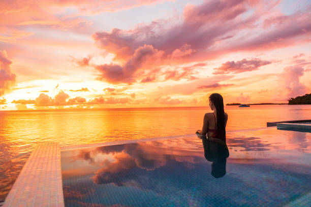 paraíso puesta de sol idílica mujer de vacaciones silueta nadando en piscina infinita mirando los reflejos del cielo sobre el sueño del océano. perfecto destino de viaje increíble en bora bora, tahití, polinesia francesa. - swimming pool resort swimming pool poolside sea fotografías e imágenes de stock