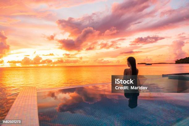 Paradise Sunset Idyllic Vacation Woman Silhouette Swimming In Infinity Pool Looking At Sky Reflections Over Ocean Dream Perfect Amazing Travel Destination In Bora Bora Tahiti French Polynesia Stock Photo - Download Image Now