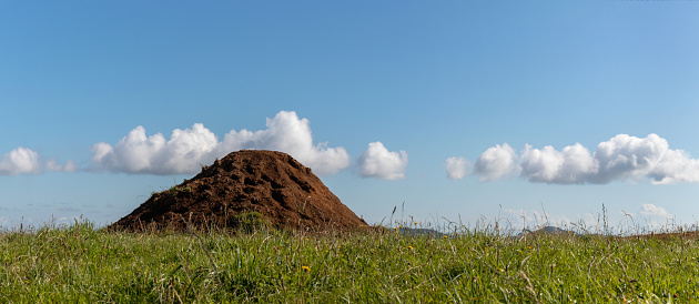 Top soil pile on green meadow and blue sky background