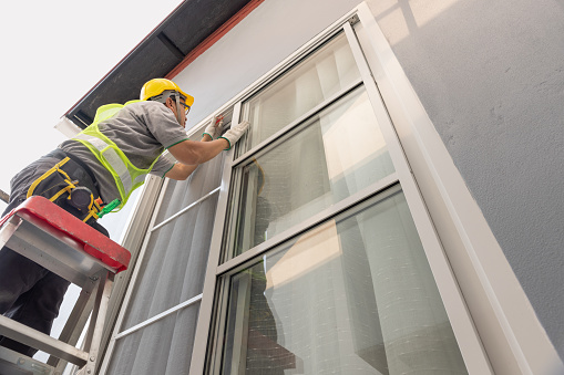 Construction worker repairing the sliding window. Open cap of adjust rail wheel.