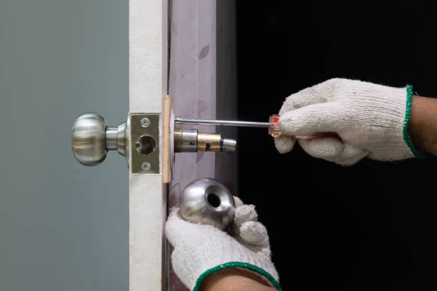 Locksmith on wood door with screwdriver for repair or fix silver knob. stock photo