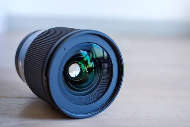 istock camera lens lying on wooden floor against white wall background 1482512857
