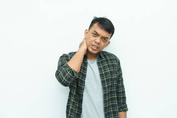 istock Young Asian man holding his neck while grimacing in pain 1482513817