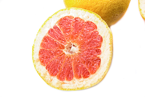Top view of a vertical composition of slices and halves of grapefruits on a blue background.