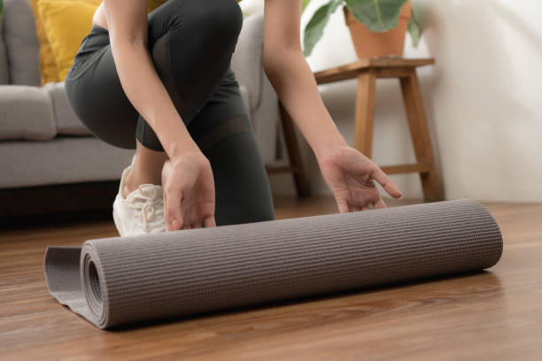 Yoga at home rolling exercise mat in living room for meditation yoga stock photo