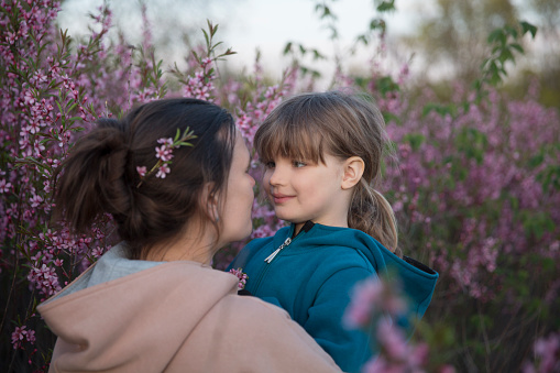 Spring awakening. Slow life. Enjoying the little things. Dreaming of spring. mom and child daughter hug each other in cherry blossoms