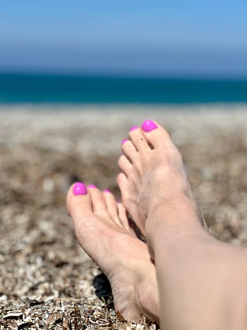 Female feet with pedicure on the beach