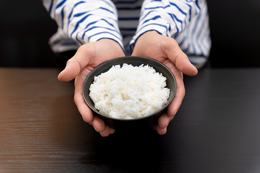 man's hand holding a teacup with hot rice