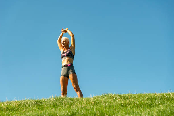 Senior Woman Stretching after Jogging in nature near the sea. The Netherlands. Low angle view.