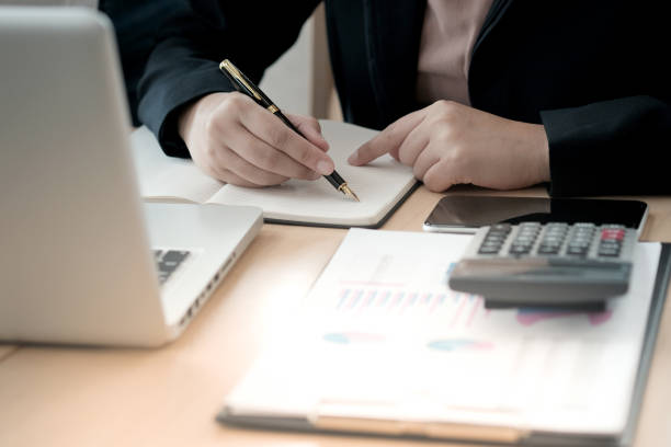 istock Businesswoman analyzing investment charts and pressing calculator buttons over documents. Accounting Concept. 1482544846