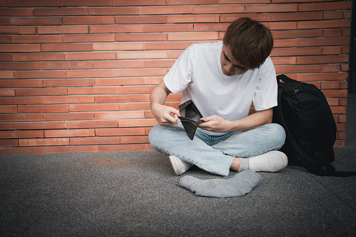 A desperate Asian opening wallet and looks at his empty wallet. Unhappy Asian people with no cash in their purses, bankrupt economic financial , Poverty in retirement, and unemployment concept.