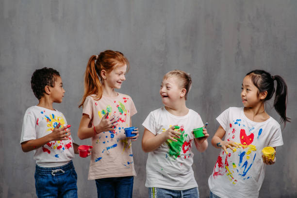 Portrait of happy kids with finger colours and painted t-shirts, studio shoot. stock photo