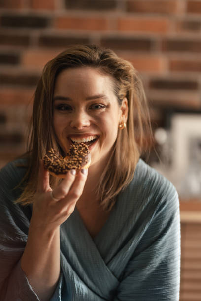 istock Young happy woman eating donuts in a cafe. 1482559213